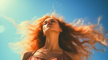 Woman With Red Hair In The Wind Against A Blue Sky