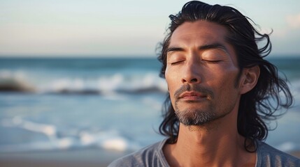 Wall Mural - Close up of handsome medium-aged meditating man with gray hair and beard on the ocean shore, with closed eyes