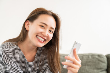 Wall Mural - 部屋でスマホを見る若い女性