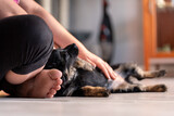 Fototapeta  - Człowiek siedzi na podłodze w domu i głaszcze wtulonego szczeniaka