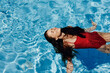 © SHOTPRIME STUDIO - Happy woman swimming in the pool in red swimsuit with loose long hair relaxed in the sunshine, skin protection with sunscreen, concept of relaxing on vacation in tropical climate, lifestyle.