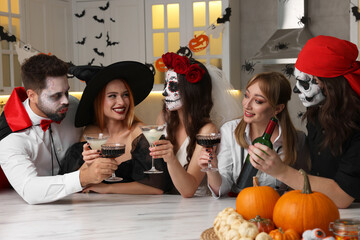 Wall Mural - Group of people in scary costumes with cocktails celebrating Halloween indoors