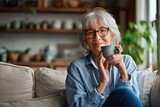 Smiling mature elder 60s woman sitting relaxing with cup of tea, coffee. Senior mid age stylish look woman with eyeglasses portrait with cup looking away at modern, Generative AI 