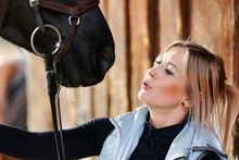 Girl Blonde In Blue Quilted Vest With Ponytail Plays With Her Horse, Portraits Of The Woman With Focus On Her Head Close-up.