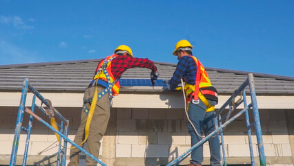 Two technicians installing solar panels on the roof of a house.