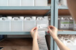 © suwanb - Beautiful young Asian chemist wears a hood, safety glasses puts a barcode sticker on a plastic bottle containing a solvent on a shelf in a stor