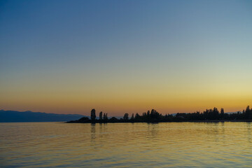 Wall Mural - Colorful sunset on the sea. Mountain lake in the rays of the orange sun. Kyrgyzstan, Lake Issyk-Kul. natural background