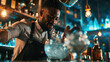 © Marta B - Focused bartender pouring a clear drink from a shaker into a glass filled with ice, with a blurred background featuring a bar environment.