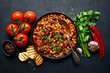 Chili con carne - traditional mexican minced meat and vegetables stew in tomato sauce in a cast iron pan . Top view with copy space.