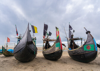 Poster - Seascape view of traditional wooden fishing boats known as moon boats on beach near Cox's Bazar, Bangladesh under moody sky