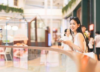 Happy asian woman city lifestyles using smartphone internet and shopping at indoors department store