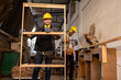 © Wanwajee - Young White man standing with window work peice with blur American Affrican men carpenter labor, craftmen working in wood workshop together with seriously in furniture industry.