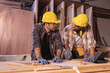© Wanwajee - Young affrican american and white men carpenter labor, craftman working in wood workshop together, looking each other. Timber industry and furniture industry.