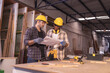 © Wanwajee - Young affrican american and white men carpenter labor, craftman working in wood workshop together. Looking paper Timber industry and furniture industry small business concept.