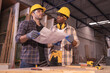 © Wanwajee - Young affrican american and white men carpenter labor, craftman working in wood workshop together. Timber industry and furniture industry small business concept.