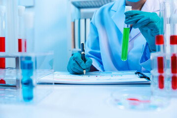 Sticker - Asian people scientist in lab coat and protective gloves working with test tubes with green and red liquids, with microscope and other test tubes in the background in laboratory.