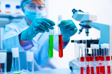 Wall Mural - Asian people scientist in lab coat and protective gloves working with test tubes with green and red liquids, with microscope and other test tubes in the background in laboratory.