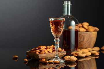 Wall Mural - Italian liqueur Amaretto with almonds nuts on a black background.