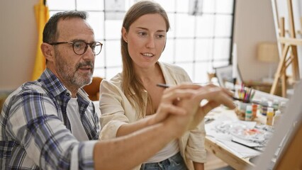 Wall Mural - Two gleaming artists, man and woman, sitting together in a bustling art studio, smiling while joyfully immersed in the process of learning to draw