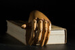 the hand rests on a closed book, which hides knowledge