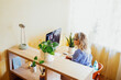 © Dasha Petrenko - Young woman sits in front of computer monitor and talks via video link.