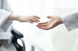 © 상은 신 - Close-up frontal shot of wheelchair patient reaching for doctor's hand in hospital setting