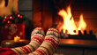 © Aura - feet in woollen socks by the Christmas fireplace. Woman relaxes by warm fire with a cup of hot drink and warming up