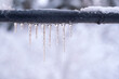 Frozen icicles on a gray pipe after a thaw in winter. Background. Form.