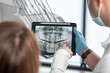 The dentist uses a tablet to visually explain the details of dental treatment so that the patient feels completely confident in her choice. Demonstrates a CT scan, an X-ray photograph