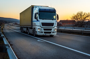 Wall Mural - Big semi trailer truck on a highway driving at bright sunny sunset. Transportation vehicle