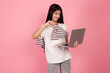 © Ирина Щукина - Young upset teenage girl and laptop shows thumb down on pink background in studio.