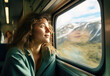 A woman gazes wistfully out the train window, her face reflecting both longing and determination as she watches the passing mountainscape in her portrait-like view