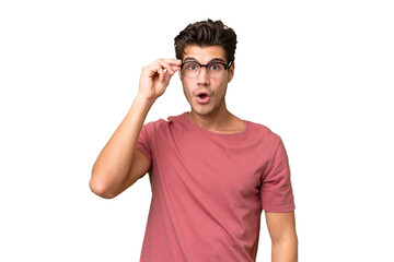 Wall Mural - Young handsome caucasian man over isolated background with glasses and surprised