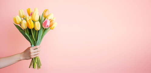  Female hand holds spring bouquet of tulips on a pink background