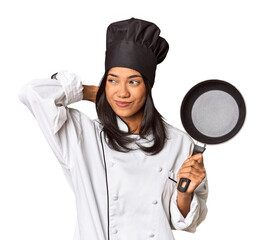 Wall Mural - Young Filipina chef holding pan by handle touching back of head, thinking and making a choice.