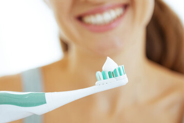 Poster - Closeup on young woman showing electric toothbrush