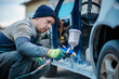 © velimir - Master car painter paints a car with a spray gun. Car painting at home.