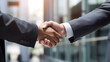 A close-up of a handshake between two business professionals in front of a modern office building symbolizing a successful deal.