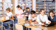 © JackF - Three schoolchildren preparing for lessons in the school library are looking for the necessary information on a laptop, ..discussing topical issues