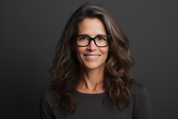 Poster - Portrait of a smiling businesswoman with glasses over dark background.