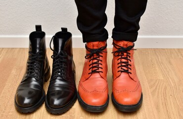 a man stands in orange shoes near a pair of black shoes with laces on the parquet floor