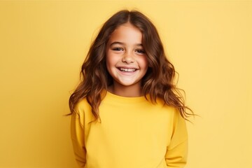 Wall Mural - Portrait of a smiling little girl in yellow sweater over yellow background