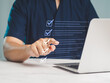 © meeboonstudio - Businessman pointed to the checklist on an online document list while sitting at a desk.