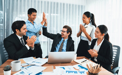 Group of happy businesspeople in high five gesture and successful efficient teamwork. Diverse race office worker celebrate after made progress on marketing planning in corporate office. Habiliment