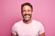© Inigo - Portrait of a happy mature man smiling and looking at camera against pink background