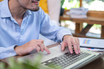 Wall Mural - Close-up freelance businessman working at indoors home office typing hand on desk computer laptop internet communication technology, human hand adult business person using laptop keyboard notebook