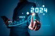 © teerawat - Businessman hand holding the increase arrow graph corporate future growth year 2023 to 2024. New Goals with Plans and Visions for Next Year 2024, Opportunity, challenge and business strategy.