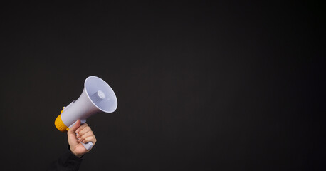 Wall Mural - Hand is hold megaphone and wear black shirt on Black background..