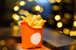 French fries or fried potatoes in a red carton box against background of Christmas garlands