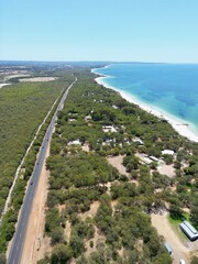 Sticker - Scenic view of a coastal highway stretching along a beach, with a few trees framing the landscape